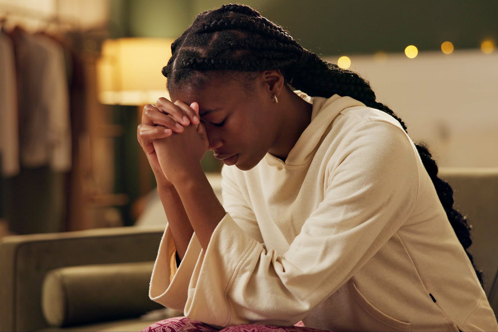 A woman, kneeling with hands folded and praying.